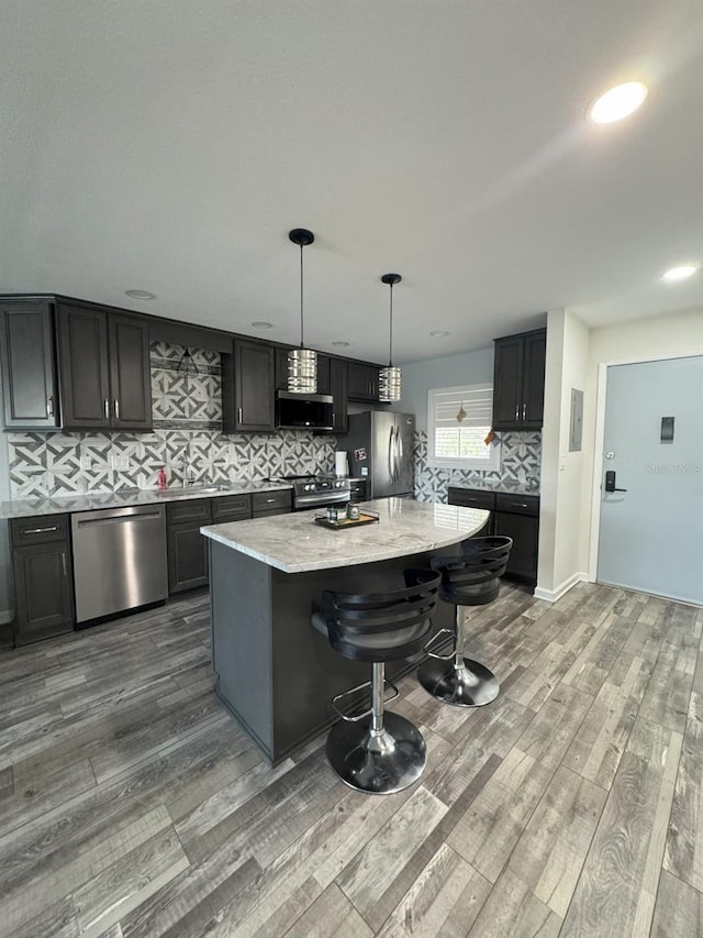 kitchen featuring hanging light fixtures, light hardwood / wood-style flooring, stainless steel appliances, and a kitchen island