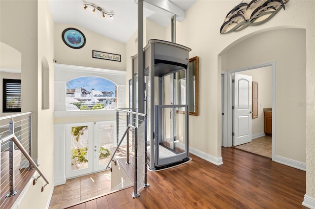 exercise area with hardwood / wood-style flooring, high vaulted ceiling, and french doors