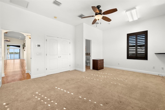 unfurnished bedroom with light colored carpet, a closet, ceiling fan, and ensuite bathroom