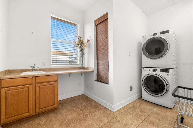 washroom with sink, light tile patterned floors, cabinets, and stacked washer / dryer