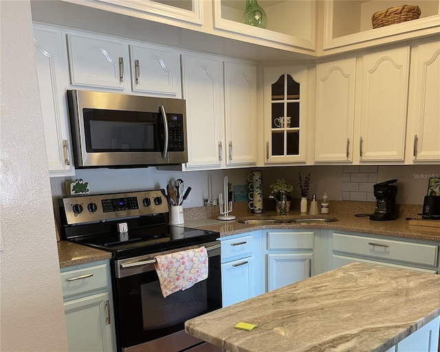 kitchen featuring sink, light stone countertops, white cabinets, and appliances with stainless steel finishes