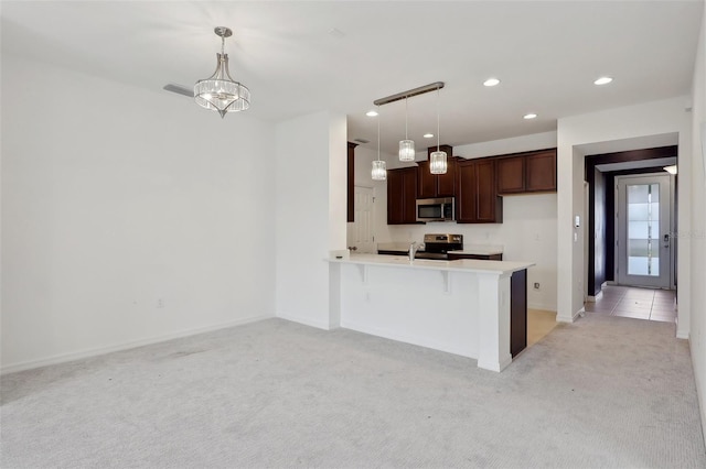 kitchen featuring appliances with stainless steel finishes, decorative light fixtures, kitchen peninsula, and light carpet