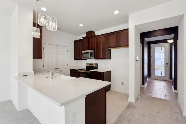 kitchen with pendant lighting, sink, light tile patterned floors, appliances with stainless steel finishes, and kitchen peninsula