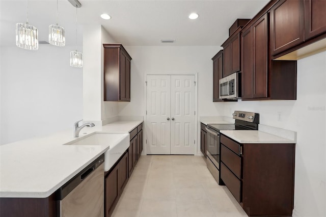 kitchen with sink, dark brown cabinets, light tile patterned floors, pendant lighting, and stainless steel appliances