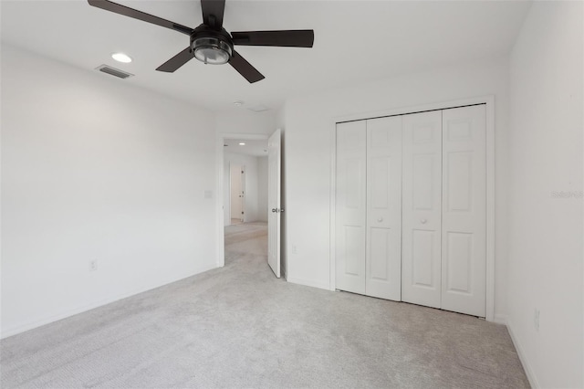 unfurnished bedroom featuring light colored carpet, ceiling fan, and a closet