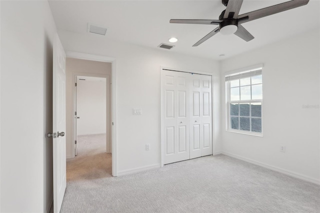 unfurnished bedroom featuring light colored carpet, ceiling fan, and a closet