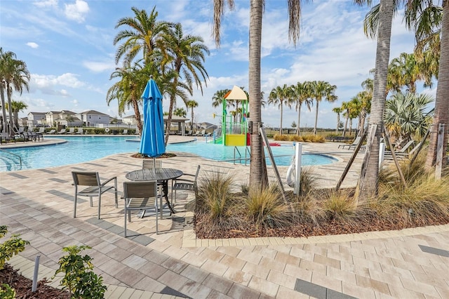 view of swimming pool with a patio area, a playground, and a water slide