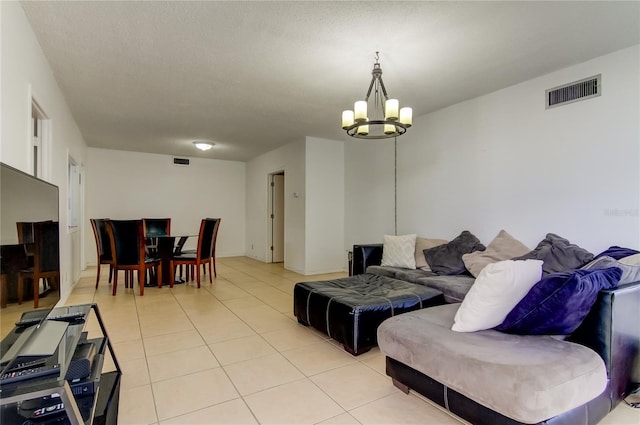 living room with an inviting chandelier, a textured ceiling, and light tile patterned floors