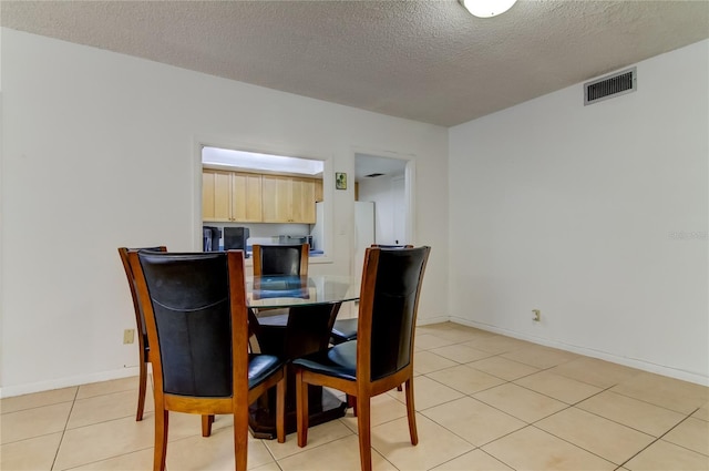 dining room featuring a textured ceiling and light tile patterned flooring