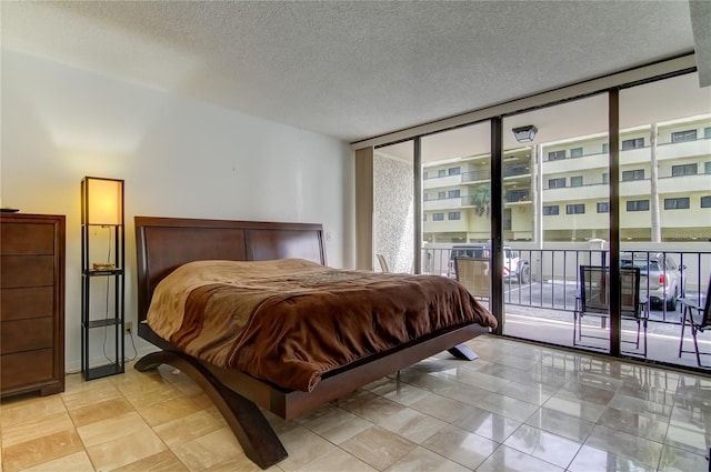 bedroom with expansive windows, a textured ceiling, and access to outside