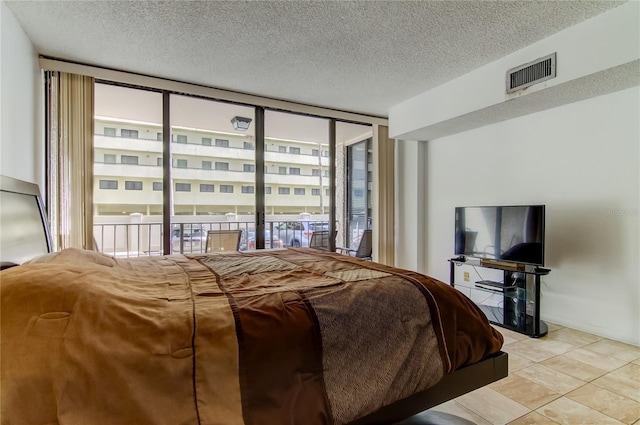 bedroom featuring access to outside, expansive windows, and a textured ceiling