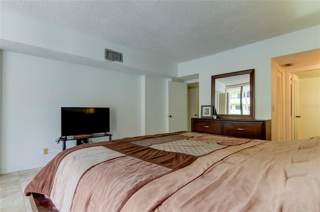 bedroom featuring light tile patterned floors and a textured ceiling