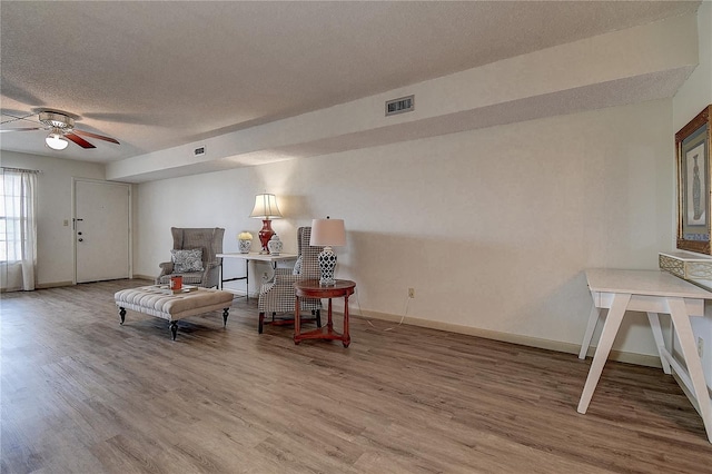 sitting room featuring a textured ceiling, wood finished floors, a ceiling fan, visible vents, and baseboards