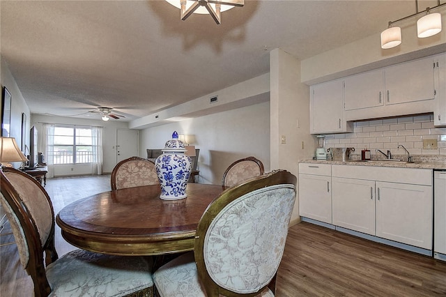 dining space featuring dark wood-style floors, a textured ceiling, and a ceiling fan