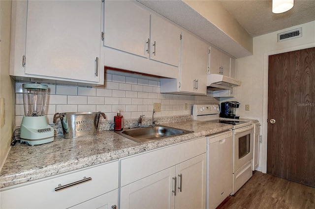 kitchen with visible vents, electric stove, under cabinet range hood, white cabinetry, and a sink