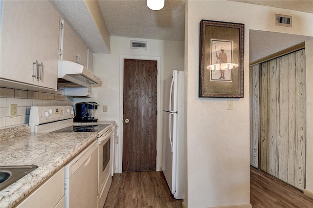 kitchen featuring light wood finished floors, white appliances, visible vents, and under cabinet range hood
