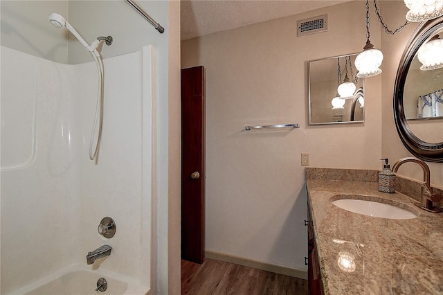 full bath with visible vents, wood finished floors, tub / shower combination, a textured ceiling, and vanity
