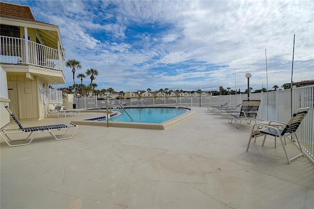 community pool with a patio and fence