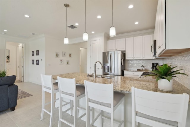 kitchen featuring pendant lighting, sink, stainless steel appliances, light stone countertops, and white cabinets