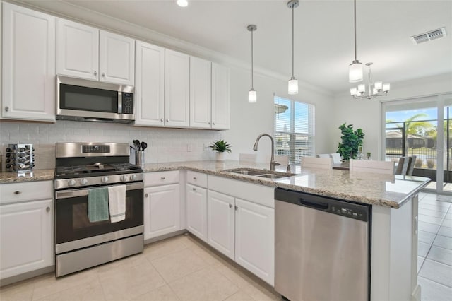 kitchen with sink, crown molding, hanging light fixtures, appliances with stainless steel finishes, and white cabinets