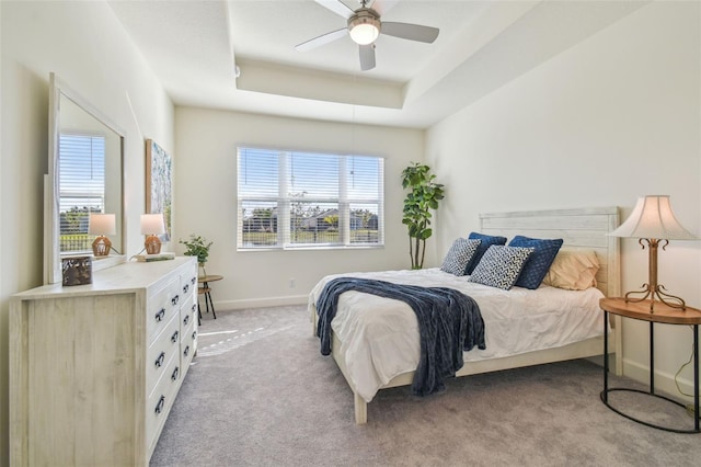 carpeted bedroom featuring ceiling fan and a tray ceiling