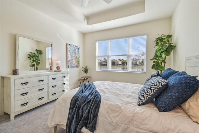 carpeted bedroom featuring a tray ceiling and ceiling fan