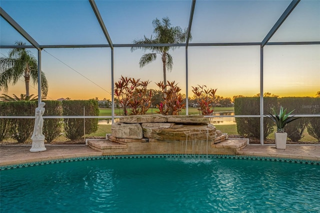 pool at dusk featuring a lanai, pool water feature, and a patio area