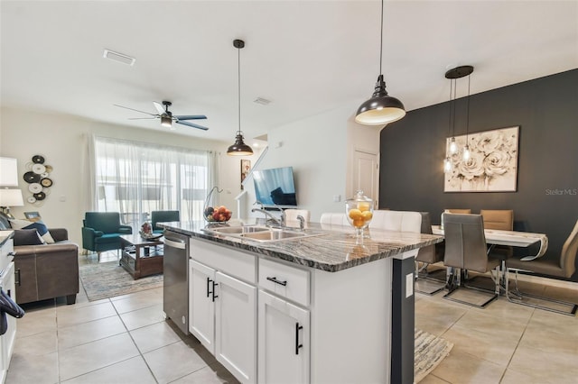 kitchen featuring hanging light fixtures, white cabinetry, stainless steel dishwasher, and an island with sink