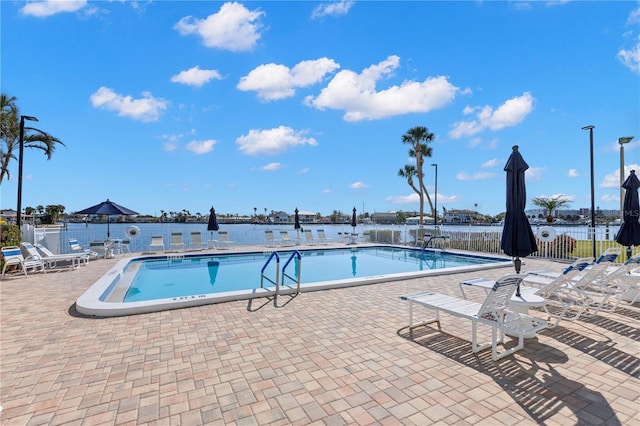 view of pool featuring a water view and a patio area