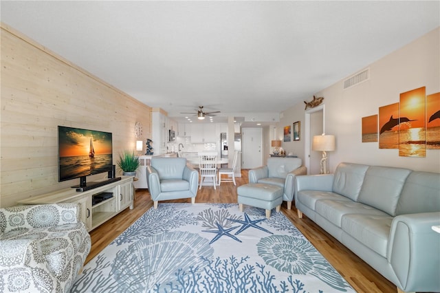 living room featuring ceiling fan, sink, and light hardwood / wood-style floors