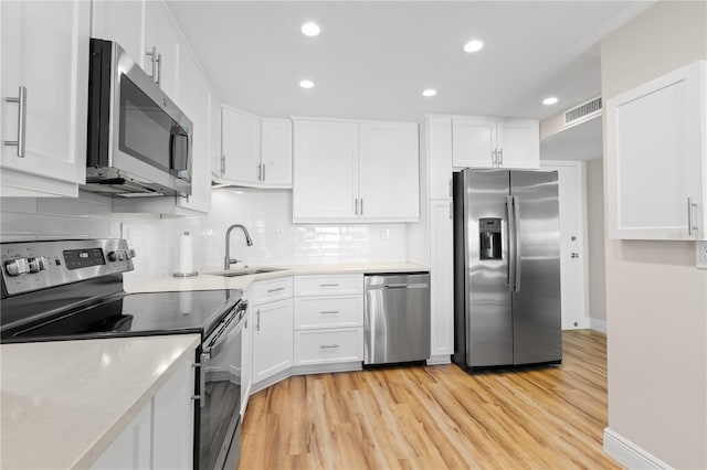 kitchen with white cabinetry, appliances with stainless steel finishes, light hardwood / wood-style floors, and sink