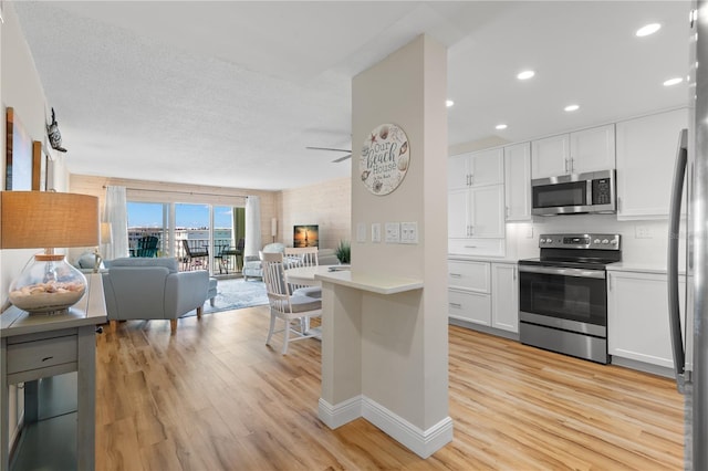 kitchen featuring stainless steel appliances, white cabinetry, backsplash, and light hardwood / wood-style flooring