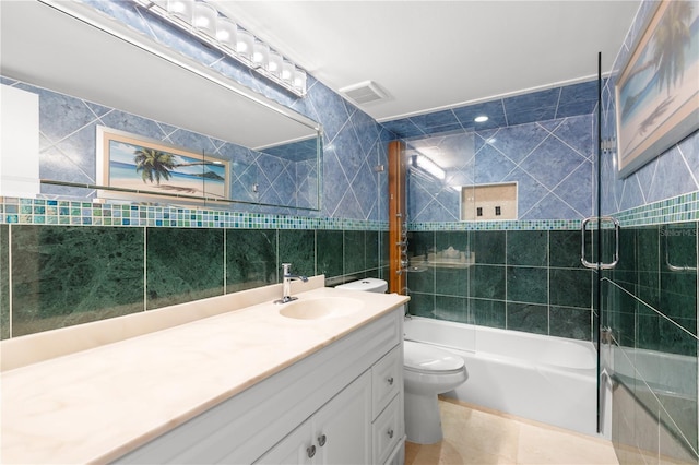 full bathroom featuring tiled shower / bath, tile walls, vanity, toilet, and tile patterned floors