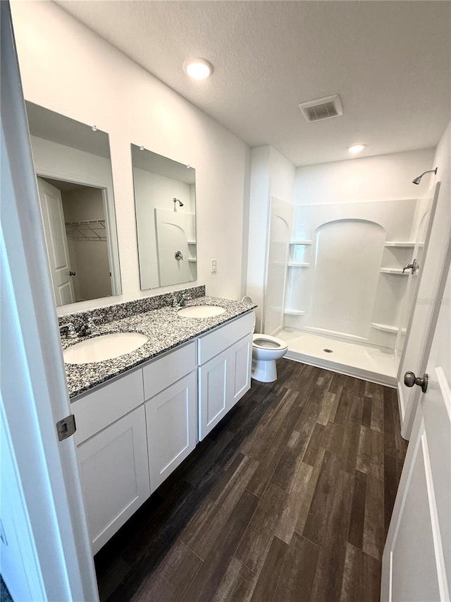 bathroom with hardwood / wood-style floors, vanity, a textured ceiling, a shower, and toilet