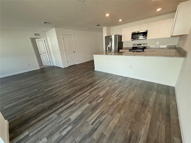 kitchen featuring stone countertops, white cabinets, dark hardwood / wood-style flooring, kitchen peninsula, and stainless steel appliances