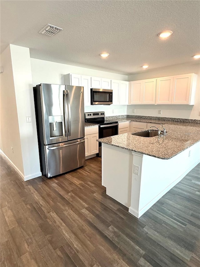 kitchen featuring sink, appliances with stainless steel finishes, white cabinets, stone countertops, and kitchen peninsula