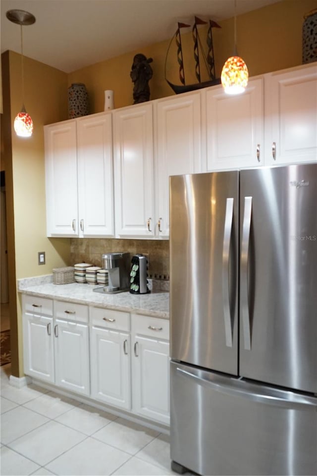 kitchen featuring stainless steel refrigerator, pendant lighting, light stone countertops, and white cabinets