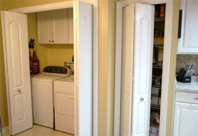 washroom with washing machine and dryer, cabinets, and light tile patterned flooring