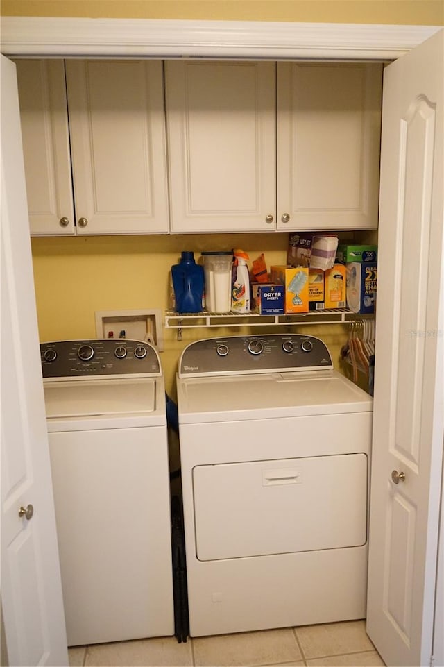 washroom with cabinets, washer and clothes dryer, and light tile patterned floors