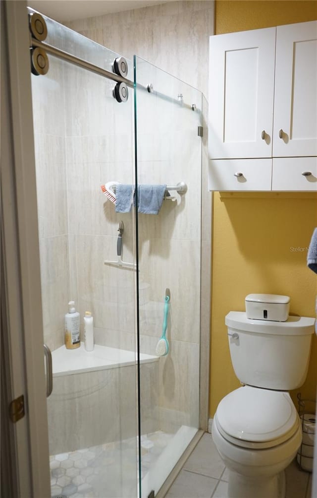 bathroom featuring a shower with door, tile patterned floors, and toilet