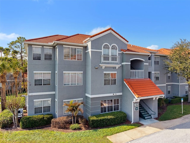 view of front of home with a tile roof, a balcony, and stucco siding