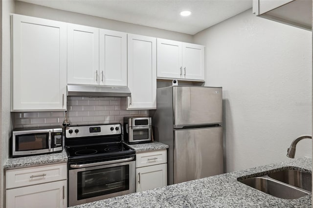 kitchen featuring tasteful backsplash, appliances with stainless steel finishes, under cabinet range hood, white cabinetry, and a sink