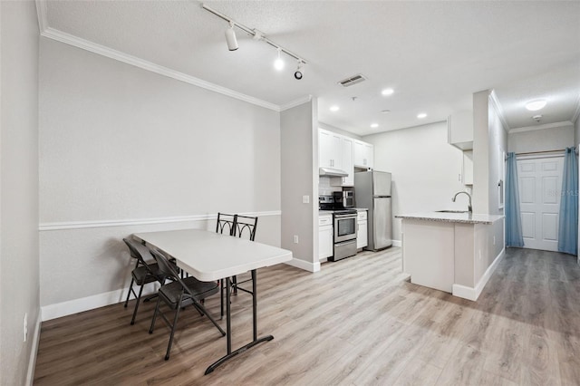 kitchen with white cabinets, light wood-style floors, appliances with stainless steel finishes, crown molding, and under cabinet range hood