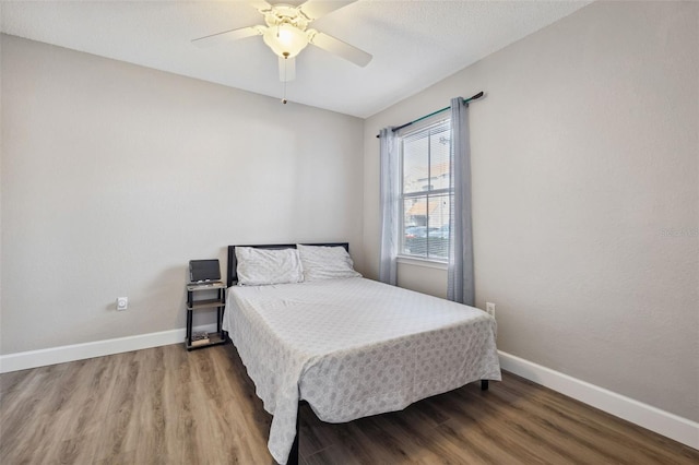 bedroom with a ceiling fan, baseboards, and wood finished floors