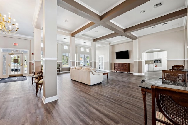 living area featuring dark wood-style floors, arched walkways, beam ceiling, a notable chandelier, and visible vents