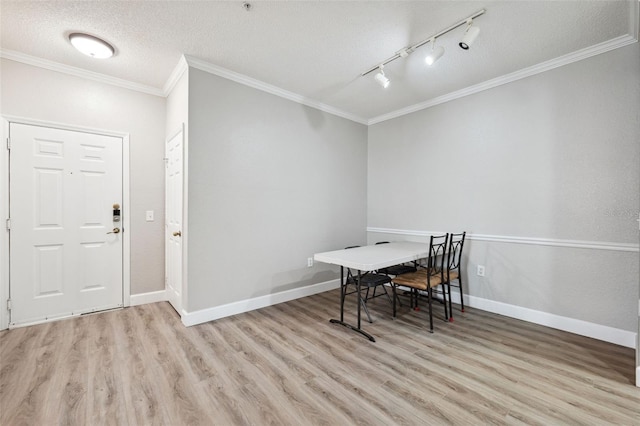 dining area with rail lighting, ornamental molding, a textured ceiling, wood finished floors, and baseboards