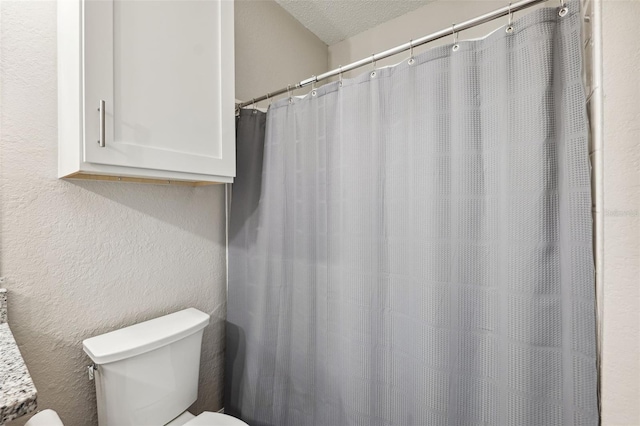 bathroom with a textured ceiling, a textured wall, and toilet