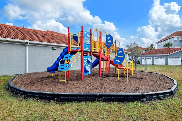 community jungle gym featuring fence and a lawn