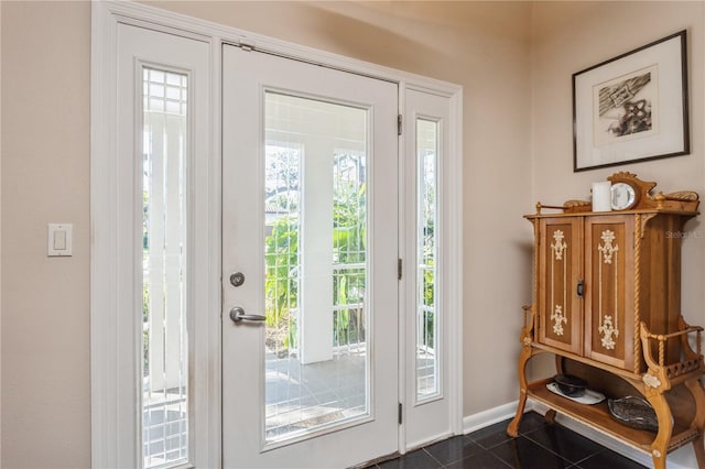 doorway featuring dark tile patterned floors and baseboards