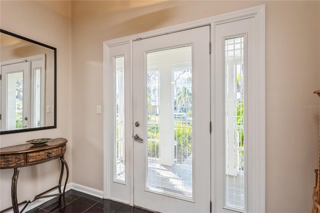 entrance foyer with dark tile patterned flooring and baseboards